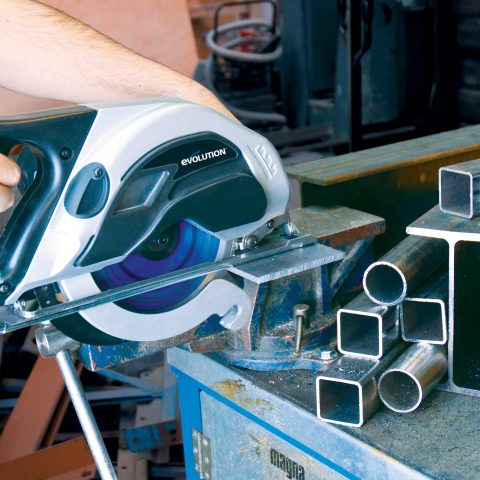 En person som använder en Evolution S185CCSL Metallcirkelsåg inkl klinga för att skära igenom ett metallrör på en arbetsbänk.