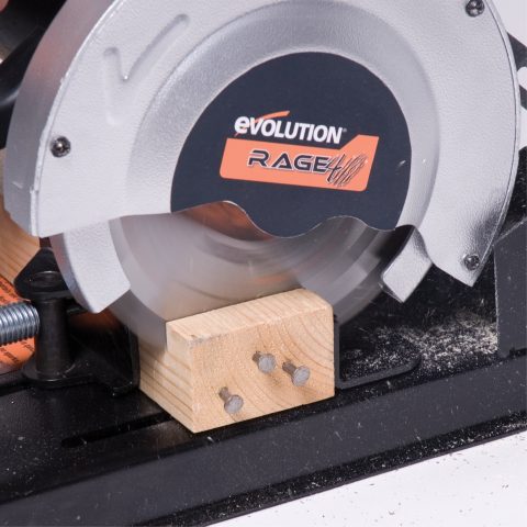 Evolution Rage 4 bänkcirkelsåg med 185mm klinga skär genom en träplanka med spik.