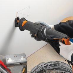Person som använder ett Evolution R230CPS Tigersåg 230V oscillerande multiverktyg för att skära en fyrkantig öppning i en vägg.