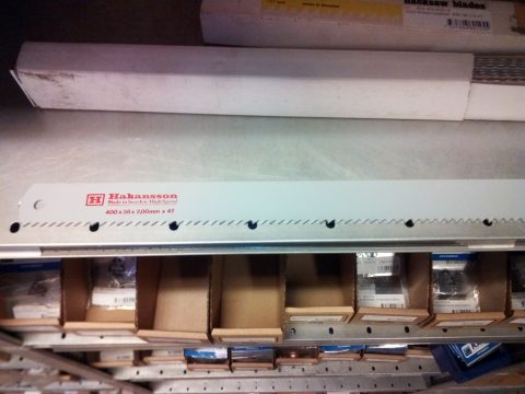 Ett Maskinsågblad 400x40x2,00-4T på en detaljhandelshylla med lådor med sågblad i bakgrunden.